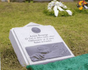 Gedenkstein mit mehrsprachiger Aufschrift in Romanes, Rumänisch und Deutsch: "Ruhet in Frieden".